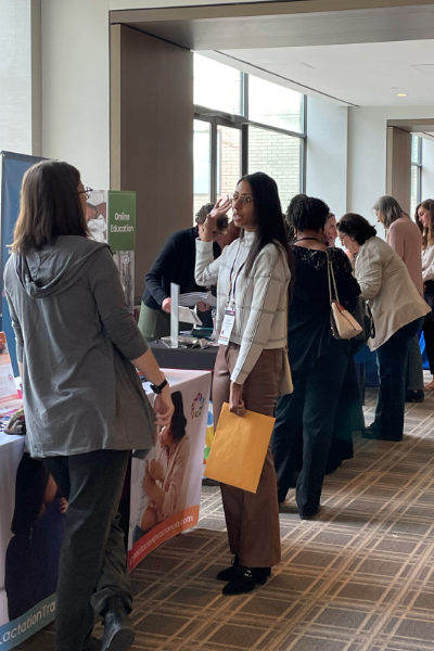 Photo of past conference attendees engaging with exhibitors