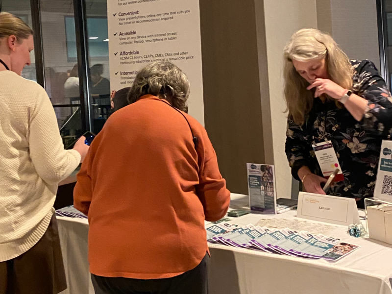 Image of a two attendees visiting an exhibitor table